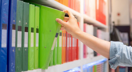 person choosing green binder off of shelf